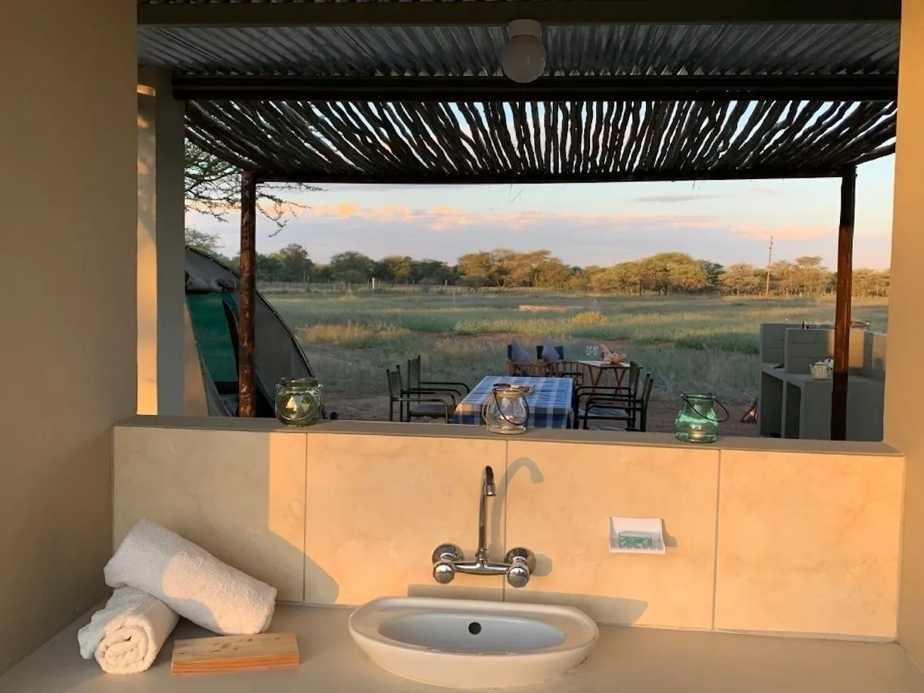 Campsite kitchen area with a sink, looking out over the bush at sunset